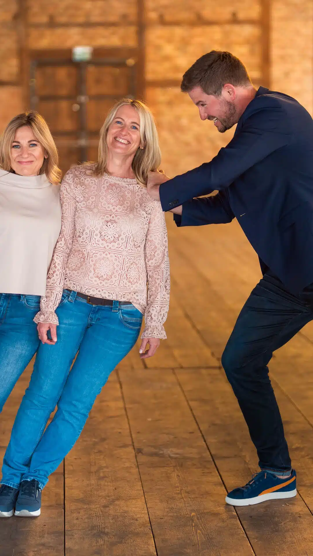 Drei Frauen lehnen sich auf die Seite, ein Mann stemmt sich dagegen.