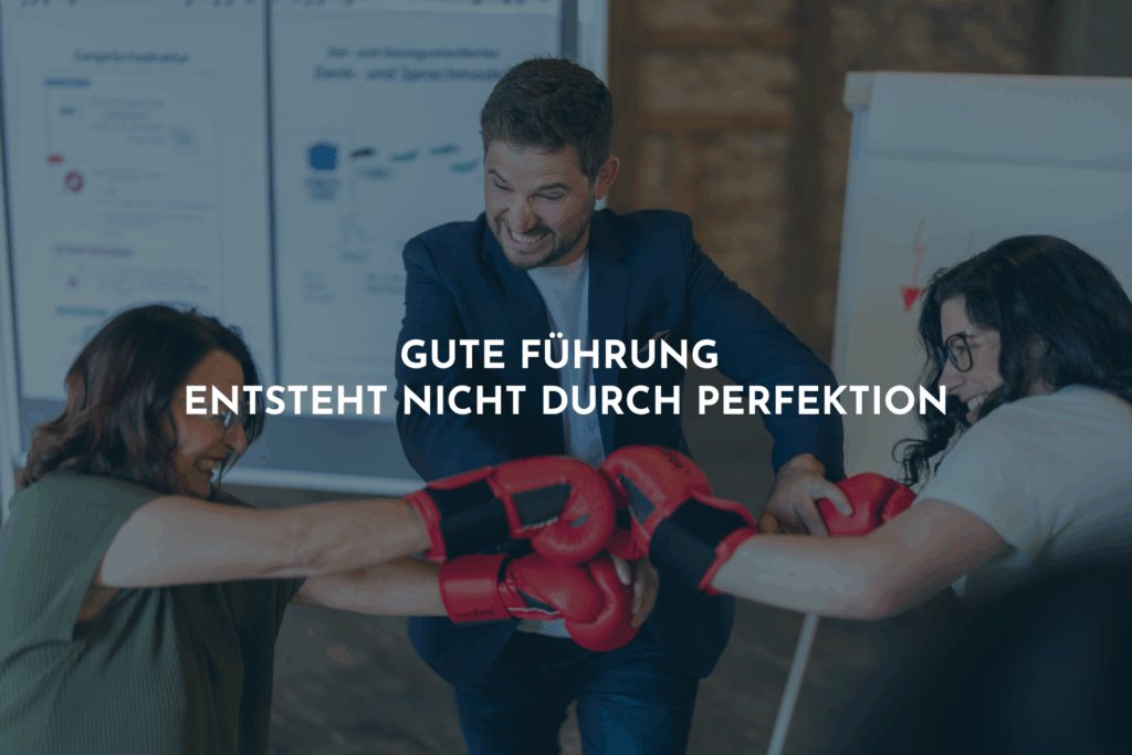 Zwei Frauen mit roten Boxhandschuhen schlagen aufeinander ein. Sie lachen dabei. Ein Mann geht dazwischen.