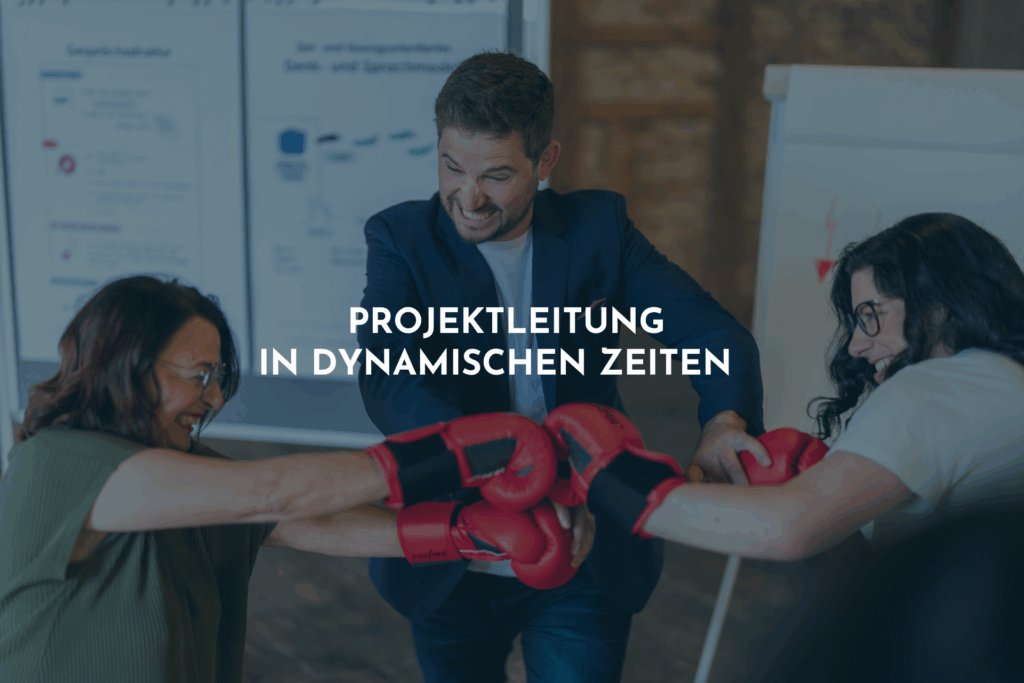 Zwei Frauen boxen und lachen dabei. Ein Mann versucht die beiden zu trennen, indem er die roten Boxhandschuhe auseinanderdrückt.